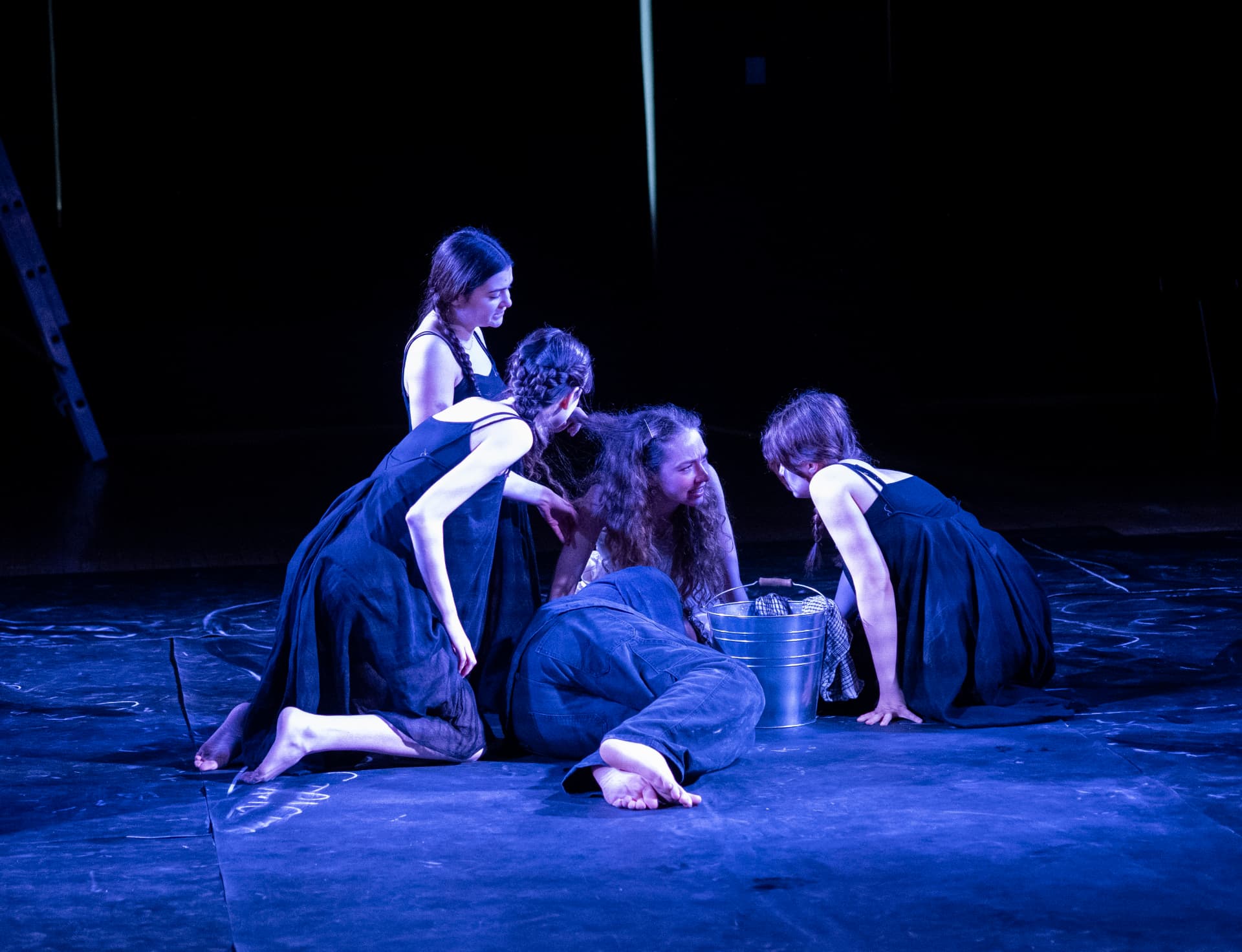 The Stones chorus gathered around Eurydice under overhead blue.