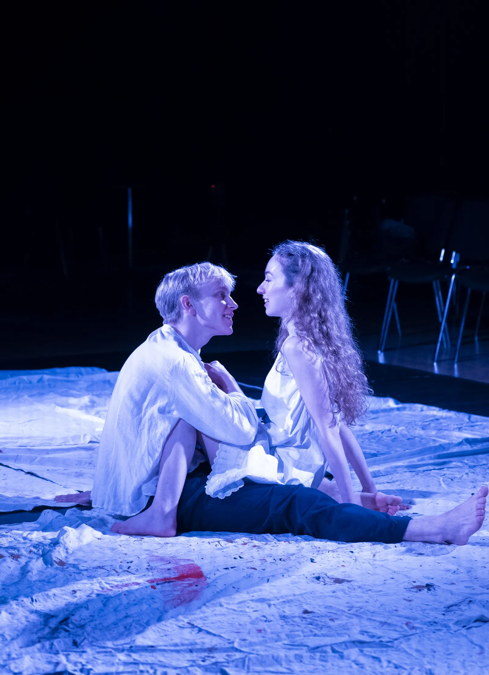 Eurydice and Orpheus seated close together on the white cloth.