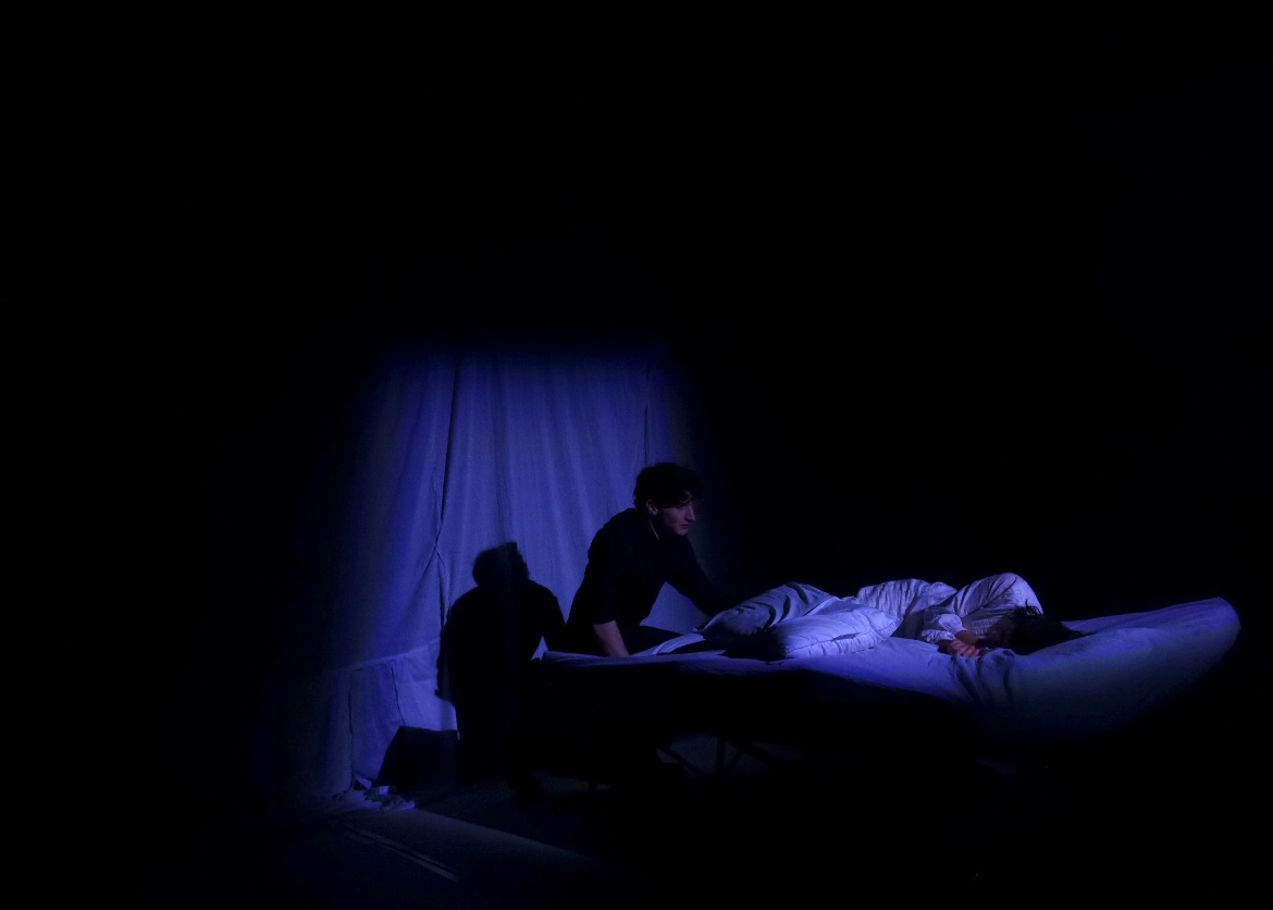 Bosola leaning over the sleeping Duchess in a pool of dim blue.