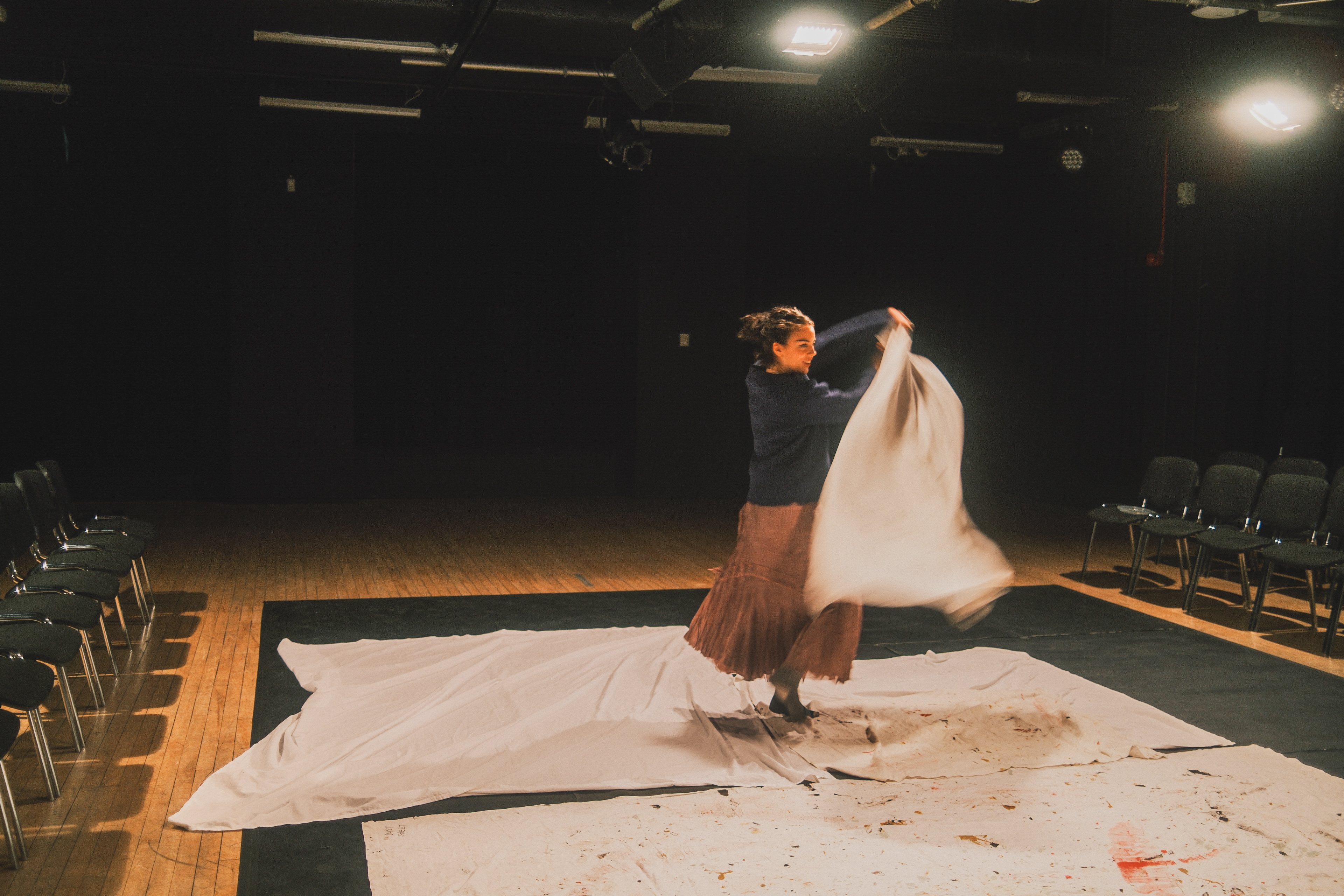 Martha Pardue throwing a sheet across the stage in rehearsal.